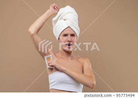 Young woman doing hair removing procedures and feeling upleased Young woman doing hair removing procedures and feeling upleased 95773494