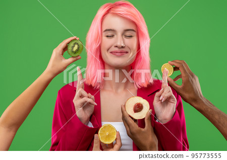 Pleased female posing for the camera against the green background Pleased female posing for the camera against the green background 95773555