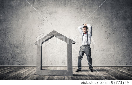 Determined banker man in empty concrete room breaking dollar figure 95773559