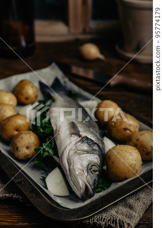 Sea Bass Filled with Sorrel Ready for Baking with New Potatoes and Onion Sea Bass Filled with Sorrel Ready for Baking with New Potatoes and Onion 95774179