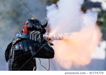 Armored warrior shooting a matchlock gun 95774779