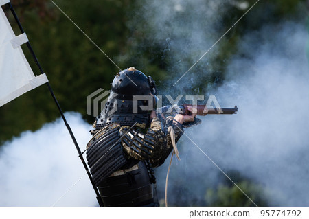 Armored warrior shooting a matchlock gun 95774792