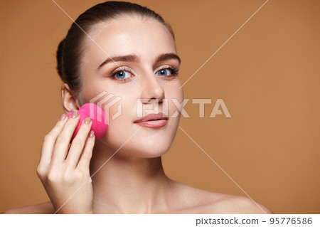 attractive young woman using pink cosmetic sponges attractive young woman using pink cosmetic sponges 95776586