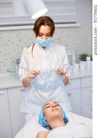 beautician removing mask from face of beautiful woman 95776602