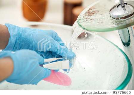 female hands in gloves wash a cosmetic spatula 95776660