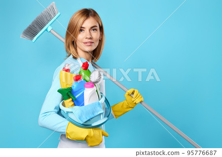 woman in gloves holding bucket of detergents and broom woman in gloves holding bucket of detergents and broom 95776687