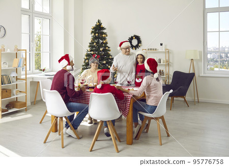 Older family member makes toast during traditional festive family Christmas dinner. Older family member makes toast during traditional festive family Christmas dinner. 95776758