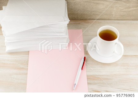 everyday life of an office worker - monotonous stack of envelopes, a sheet of pink paper and pen lie ahead on the desktop, with a fresh Cup of green tea is next 95776905