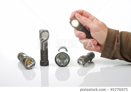 hand holds a flashlight against the background of other flashlights 95776975