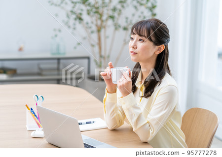 A woman teleworking in the living room. 95777278