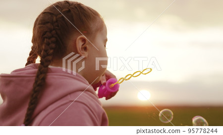 child blowing soap bubbles sunset. kid plays by inflating large transparent balloons. soap game kindergarten. chidhood dream. girl daughter evening plays with soap bubbles against sky. happy family. child blowing soap bubbles sunset. kid plays by inflating large transparent balloons. soap game kindergarten. chidhood dream. girl daughter evening plays with soap bubbles against sky. happy family. 95778244