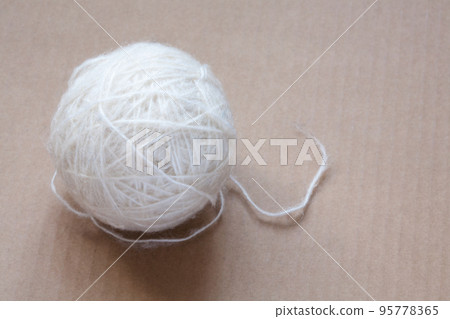 Ball of white wool yarn on cardboard background Ball of white wool yarn on cardboard background 95778365