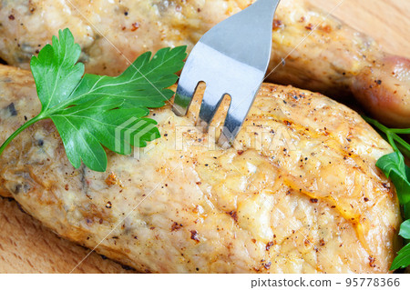 Pierce the chicken with a fork on a cutting board Pierce the chicken with a fork on a cutting board 95778366