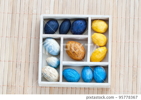 Box with colored nuts on a bamboo napkin Box with colored nuts on a bamboo napkin 95778367