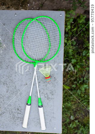 Green badminton rackets on the table. Outdoor sports, active recreation. View from above. Sports equipment. 95778419