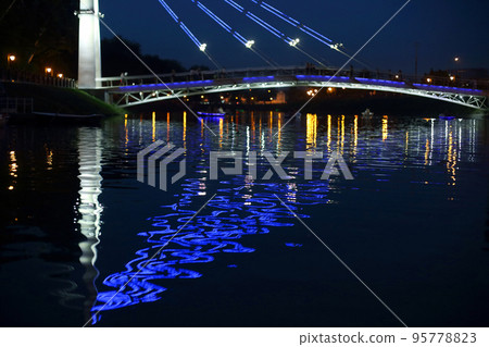 reflected night lighting of the bridge in the river 95778823