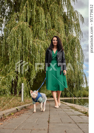 Woman walking with cat on a leash outdoor. Concept of Pet care, cat on harness, daily walking, jogging, training, and any outdoor recreations with lovely pet. Girl pet owner carries her cat Woman walking with cat on a leash outdoor. Concept of Pet care, cat on harness, daily walking, jogging, training, and any outdoor recreations with lovely pet. Girl pet owner carries her cat 95779632