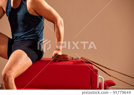 Pilates reformer workout exercises man at gym indoor. 95779649