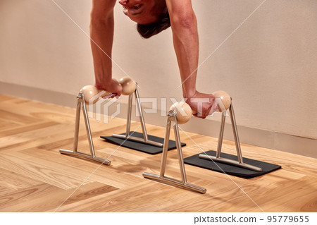 Fit man doing a lunge stretch yoga pilates exercise to strengthen and tone his muscles using a reformer in a gym 95779655