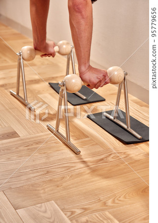 Fit man doing a lunge stretch yoga pilates exercise to strengthen and tone his muscles using a reformer in a gym 95779656
