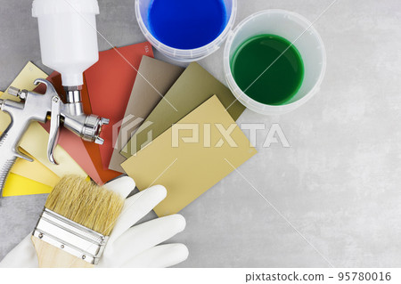 Instructions and a paint spray gun at work at the workplace in the workshop. 95780016