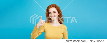Portrait of young stylish freckled girl laughing with showing thumps up at camera. Copy space. Portrait of young stylish freckled girl laughing with showing thumps up at camera. Copy space. 95780554