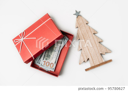 How To Spend, Christmas budget and saving concept. Xmas gift box, Stack of dollar bills and wooden Christmas tree on white table How To Spend, Christmas budget and saving concept. Xmas gift box, Stack of dollar bills and wooden Christmas tree on white table 95780627