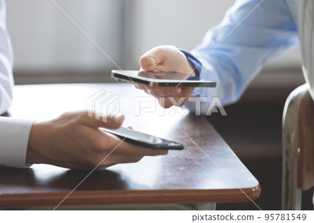 Two students operating smartphones 95781549