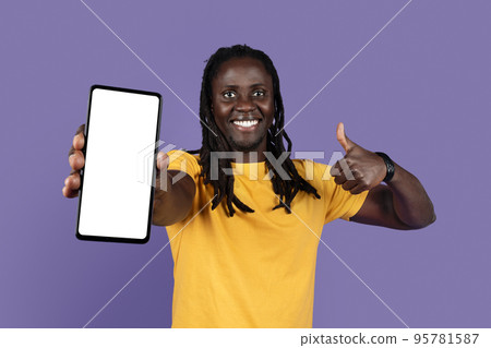 Cheerful cool black guy showing cell phone and thumb up Cheerful cool black guy showing cell phone and thumb up 95781587