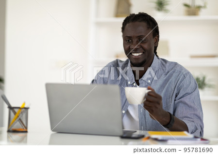 Distance Work. Happy Black Freelancer Guy Drinking Coffee And Using Laptop 95781690