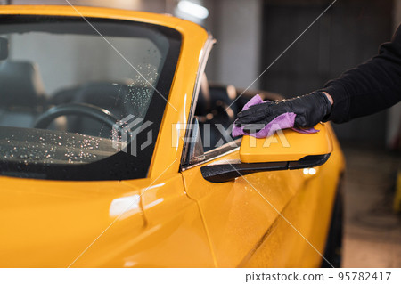 Close up of hand of male car service worker hand in black rubber glove holding the microfiber cloth Close up of hand of male car service worker hand in black rubber glove holding the microfiber cloth 95782417