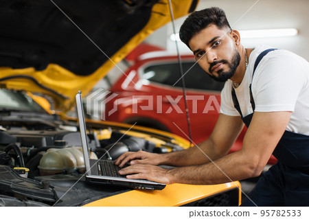 Car mechanic maintains vehicle using diagnostic laptop computer for checking engine problems Car mechanic maintains vehicle using diagnostic laptop computer for checking engine problems 95782533
