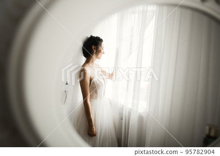 Luxury bride in white dress posing while preparing for the wedding ceremony Luxury bride in white dress posing while preparing for the wedding ceremony 95782904