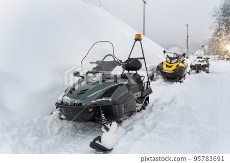 Front scene view many modern snow mobile scooter atv vehicle forest road against woods on cold snowy winter day. Snowmobile rental sport adventure trip service. Arctic nordic snow sledge transport Front scene view many modern snow mobile scooter atv vehicle forest road against woods on cold snowy winter day. Snowmobile rental sport adventure trip service. Arctic nordic snow sledge transport 95783691