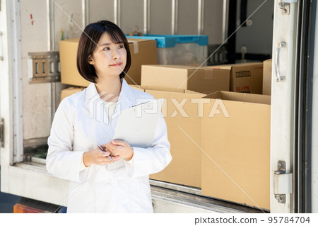 一個穿白大褂的女人在卡車上檢查行李 95784704