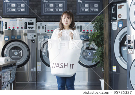 洗衣店裡帶洗衣袋的年輕女子 95785327