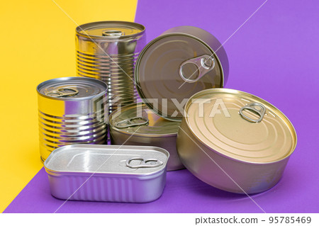 A Group of Stacked Tin Cans with Blank Edges on Split Yellow and Violet Background A Group of Stacked Tin Cans with Blank Edges on Split Yellow and Violet Background 95785469