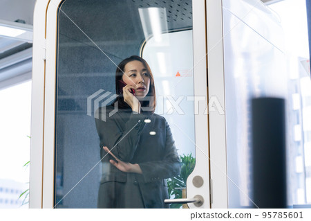 Business woman making a phone call in a private room work booth Business woman making a phone call in a private room work booth 95785601