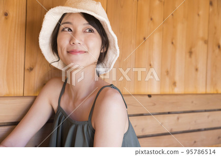 Sauna girl wearing a sauna hat and entering the sauna 95786514