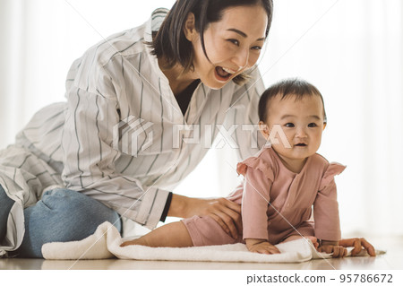 Baby trying to stand up and mother comforting Baby trying to stand up and mother comforting 95786672
