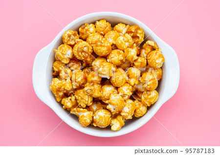 Honey caramel popcorn on pink background. Honey caramel popcorn on pink background. 95787183