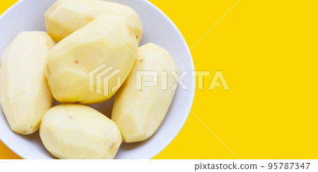 Raw peeled potatoes on yellow background 95787347