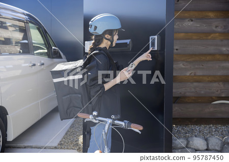 Food delivery image A young woman pressing the intercom button Shared delivery 95787450