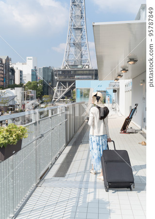 A young woman pulling a suitcase and sightseeing in Nagoya 95787849