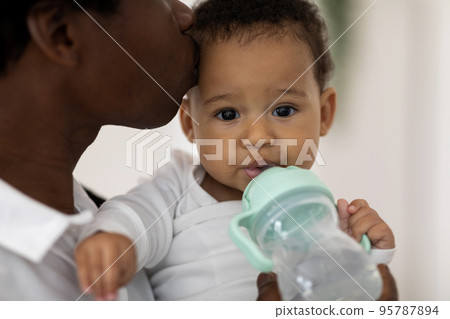 Closeup Portrait Of Thirsty Adorable Black Infant Boy Drinking Water From Bottle 95787894