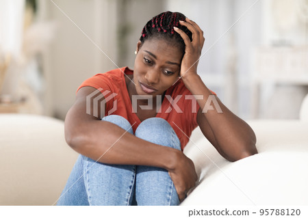 Portrait Of Depressed Young Black Woman Sitting On Couch At Home Portrait Of Depressed Young Black Woman Sitting On Couch At Home 95788120