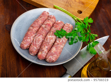 Plate with raw Catalan sausages botifarra and greens prepared for cooking Plate with raw Catalan sausages botifarra and greens prepared for cooking 95788319