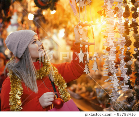 Positive smiling woman at fair near counter with Christmas gifts Positive smiling woman at fair near counter with Christmas gifts 95788416