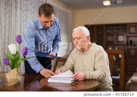 Mature man and realtor fills in documents for purchase of apartment 95788714