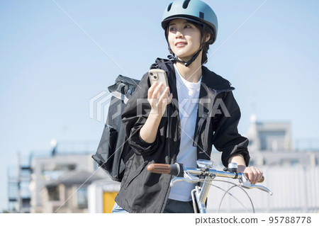 Food delivery image A delivery woman checking the destination on her smartphone Food delivery image A delivery woman checking the destination on her smartphone 95788778